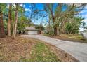 Street view of the two story home featuring mature landscaping, a long driveway, and a two car garage at 2151 E Leewynn Dr, Sarasota, FL 34240