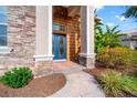 Inviting front entryway with a blue glass door, brick pathway, and lush landscaping at 21537 Draycott Way, Land O Lakes, FL 34637