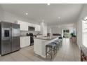 Open-concept kitchen featuring stainless steel appliances, a granite countertop island with barstool seating, and seamless flow to living area at 3664 Zephyr Preserve Pl, Zephyrhills, FL 33541