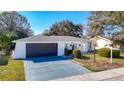 Charming single-story home with a black garage door and a gated front entrance at 714 Lemonwood Dr, Oldsmar, FL 34677