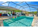 Beautiful screened-in pool with a green umbrella, beach balls, lounge chairs and slide for fun in the sun at 7426 Sungold Meadow Ct, Apollo Beach, FL 33572