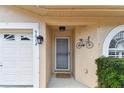 Inviting entrance featuring decorative bicycle decor, well maintained shrubbery, and direct garage access at 9012 Antigua Dr, Seminole, FL 33777