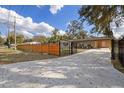 View of the front of the home with a horizontal slat fence and a concrete driveway with leaves at 934 W Wheeler Rd, Brandon, FL 33510