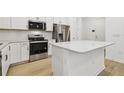 Modern kitchen featuring stainless steel appliances, white cabinetry, subway tile backsplash and hardwood floors at 13729 Evergreen Valley Dr, Riverview, FL 33578