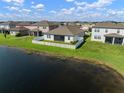 Backyard view of home from lake featuring a white fence and screen patio at 11717 Navajo Sandstone St, Riverview, FL 33579