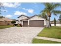 Beautiful view of the home's front exterior with a brick paver driveway and three-car garage at 1604 Harvest Grove Ct, Valrico, FL 33596