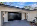 Attached two car garage with black garage door and adjacent entrance door at 16106 Blackbeard Ln, Hudson, FL 34667