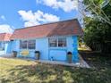 Home exterior featuring a blue facade, a brown roof, a yellow bench, and lush landscaping at 8445 Jeffrey N # 8445, Pinellas Park, FL 33781