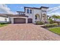 Stately two-story home featuring a three-car garage, clay tile roof, and manicured landscaping at 912 Symphony Beach Ln, Apollo Beach, FL 33572