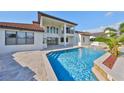 Back exterior featuring a private pool with a waterfall feature, travertine tile deck, and covered patio at 912 Symphony Beach Ln, Apollo Beach, FL 33572