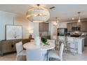 Open concept dining area with modern chandelier, white table with seating, and view of kitchen and living room at 9806 Crescent Moon Dr, Riverview, FL 33578