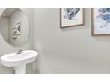 Charming powder room with a pedestal sink, decorative art and a round mirror at 11854 Davis Dr, Largo, FL 33774