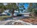 Charming single-Gathering home with blue siding, brick accents, mature landscaping, and attached two car garage at 2580 Redwood Way, Clearwater, FL 33761