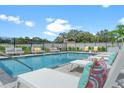 The clear blue community pool is surrounded by lounge chairs, patio furniture, and lush green landscaping at 6213 64Th N Way, Pinellas Park, FL 33781