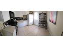 Functional kitchen featuring white cabinets, appliances, tile floor, and a shelved cart at 12413 Oak Cedar Pl # 201, Tampa, FL 33612