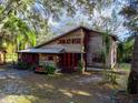 Charming two-story home with a rustic facade, red trim, and a landscaped front yard under a canopy of trees at 12950 Lincoln Rd, Riverview, FL 33578