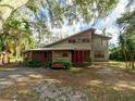 Charming two-story home with a rustic facade, red trim, and a landscaped front yard under a canopy of trees at 12950 Lincoln Rd, Riverview, FL 33578