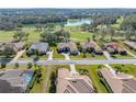 Aerial view of home, mature trees and landscaping, golf course and lake in the background at 13854 Thoroughbred Dr, Dade City, FL 33525