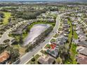 Aerial view of a residential neighborhood featuring mature trees and a scenic pond at 2449 E Del Webb Blvd, Sun City Center, FL 33573