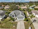 Aerial shot highlighting the property with a well-manicured lawn and mature palm trees at 2449 E Del Webb Blvd, Sun City Center, FL 33573