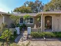 Inviting front entrance with wrought iron gate, mature landscaping, and charming architectural details at 3054 Bright Dr, Holiday, FL 34691