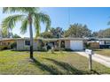 Traditional home featuring well-maintained lawn, mature palm tree, and an attached single car garage at 3054 Bright Dr, Holiday, FL 34691