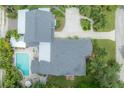 Aerial view of property featuring a backyard pool, lush landscaping, grey roof, and ample parking at 5114 N Branch Ave, Tampa, FL 33603