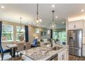 Open-concept kitchen and dining area with stainless steel appliances and granite countertop island at 6206 Timberdale Ave, Wesley Chapel, FL 33545