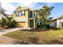 Two-story home featuring a two-car garage, well-maintained lawn, and freshly planted shrubbery under a clear, blue sky at 11539 Tangle Branch Ln, Gibsonton, FL 33534
