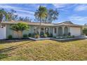 Inviting one-story home featuring a light-colored exterior, a well manicured lawn, and lush, tropical landscaping at 13330 88Th Pl, Seminole, FL 33776