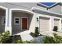 Townhouse exterior featuring a private garage, a covered porch, and well-maintained landscaping at 2411 Paravane Way, Wesley Chapel, FL 33543