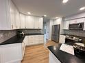 Bright kitchen featuring white cabinets, black countertops, stainless steel appliances, and stylish backsplash at 2488 Orangepointe Ave, Palm Harbor, FL 34683