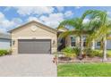 Charming one-story home with well-maintained landscaping and a brick driveway leading to the garage at 4920 Sevilla Shores Dr, Wimauma, FL 33598