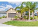 Inviting one-story home with lush tropical landscaping, brick driveway, and a neutral color scheme at 4920 Sevilla Shores Dr, Wimauma, FL 33598