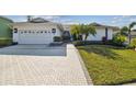 Charming single-story home featuring a well-manicured lawn, brick pathway, and a two-car garage at 944 Symphony Isles Blvd, Apollo Beach, FL 33572