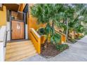 Building entrance featuring a secure wooden door and stairs, complemented by vibrant plants and colorful exterior accents at 100 4Th S Ave # 202, St Petersburg, FL 33701