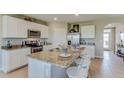 Spacious kitchen featuring a granite island with seating, stainless steel appliances, and white cabinets at 10907 Gentle Current Way, Parrish, FL 34219