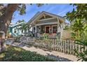 Charming home featuring a picket fence, lush landscaping, and a cozy front porch with a red front door at 731 7Th N St, St Petersburg, FL 33701