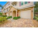 Charming townhome exterior with a one-car garage, brick paved driveway, and landscaped front yard at 876 Callista Cay Loop, Tarpon Springs, FL 34689
