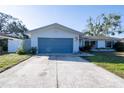 Charming single-story home with a blue garage door and a spacious concrete driveway at 1091 Mcfarland St, Dunedin, FL 34698