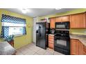 Kitchen featuring wood cabinets, black appliances, and tiled floors, illuminated by natural light at 1242 Holly Cir, Oldsmar, FL 34677