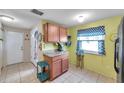 Compact kitchen with wood cabinets, tiled floor, and bright yellow walls, showcasing a functional layout at 1242 Holly Cir, Oldsmar, FL 34677