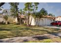 Exterior view showing a house, lawn, and mature trees with plenty of curb appeal on a sunny day at 14810 Feather Cove Ln, Clearwater, FL 33762