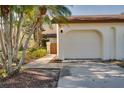 Home exterior with a two car garage, walkway to private front courtyard, and mature landscaping at 14810 Feather Cove Ln, Clearwater, FL 33762