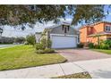 Two-story home with a manicured lawn, mature trees, and a brick driveway leading to an attached two-car garage at 17596 Terrazzo Way, Land O Lakes, FL 34638