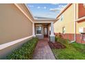 Inviting front porch with brick walkway, manicured hedges, and decorative glass front door at 17596 Terrazzo Way, Land O Lakes, FL 34638