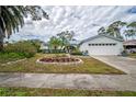 Single-story home showcasing a well-maintained lawn and mature landscaping with a flowerbed, adding curb appeal at 2086 Whitney N Pl, Clearwater, FL 33760