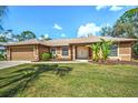 Attractive home featuring a lush lawn, double door entry, and mature landscaping at 5327 N Cranberry Blvd, North Port, FL 34286