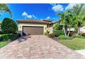 Charming home featuring a lush landscaped yard and a paver driveway leading to the attached garage at 7115 Marsh View Ter, Bradenton, FL 34212