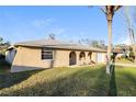 Attractive exterior elevation showcasing a well-maintained lawn, mature tree, and neutral color palette at 7825 Bolam Ave, New Port Richey, FL 34653